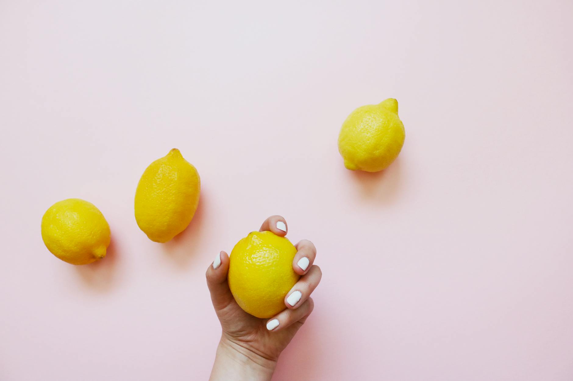 A yellow silicone clitoral vibrator on a yellow background surrounded by fresh fruit