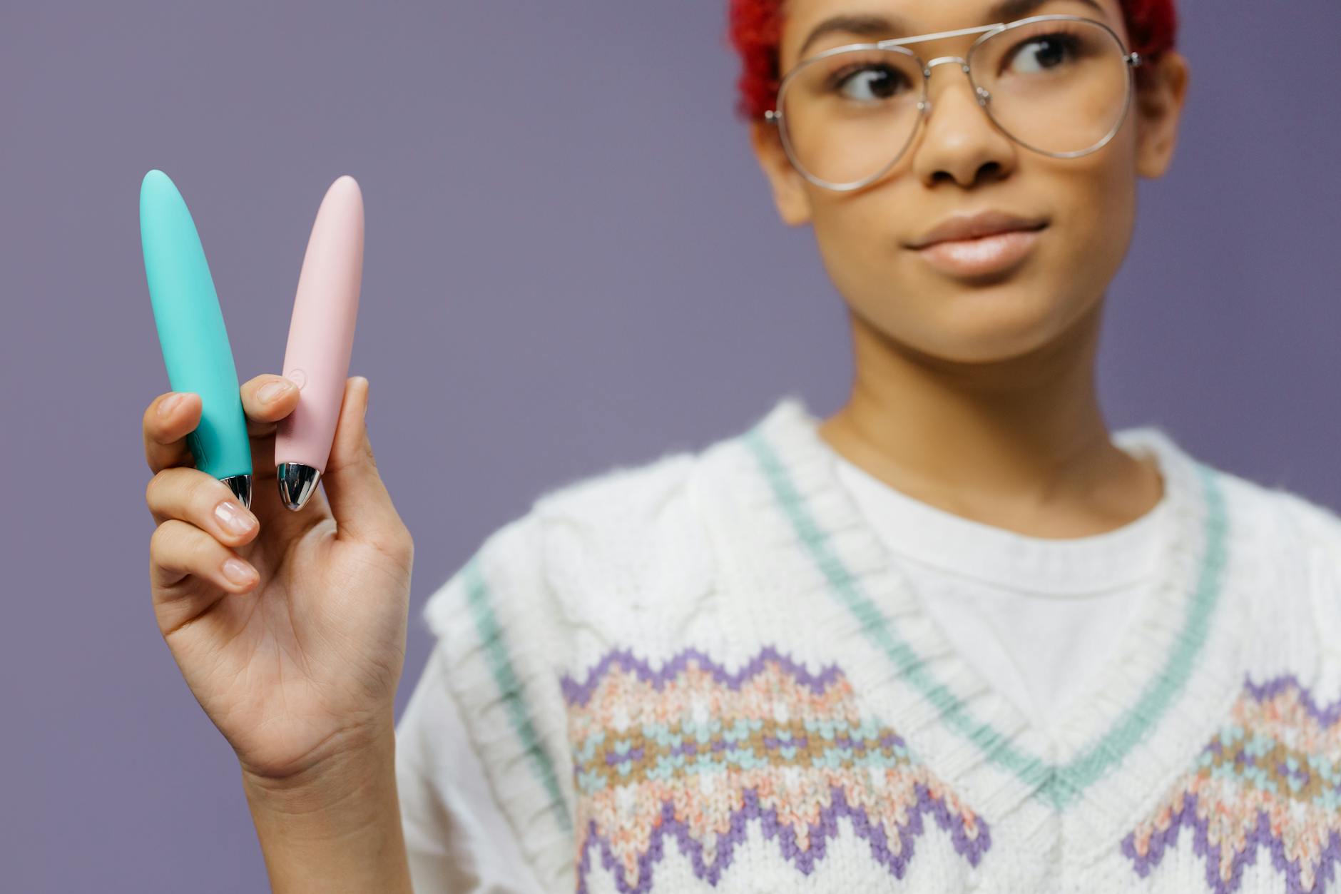 Close-up of hands holding a blue personal massager against a knitted sweater, representing intimate connection and modern pleasure solutions